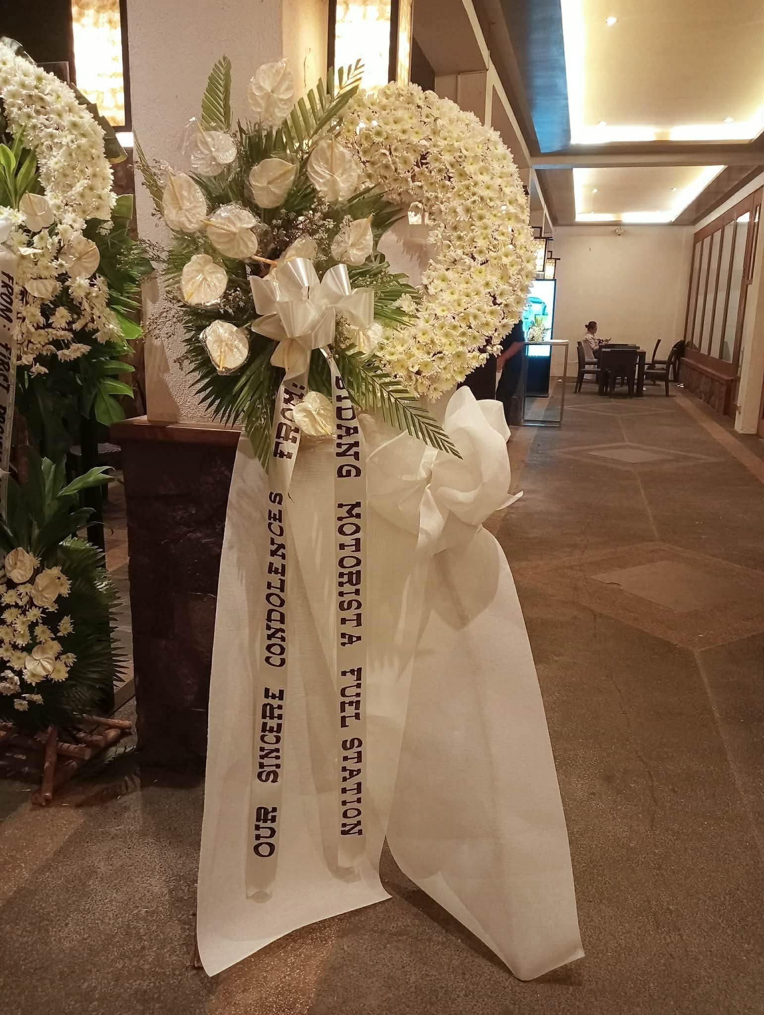 Gentle Tribute white funeral flower stand with ribbon message in Manila