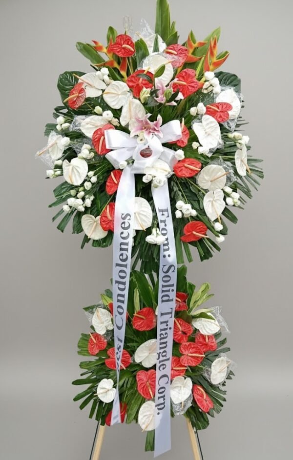 Red and white standing funeral spray with anthuriums, lilies, roses, and greenery